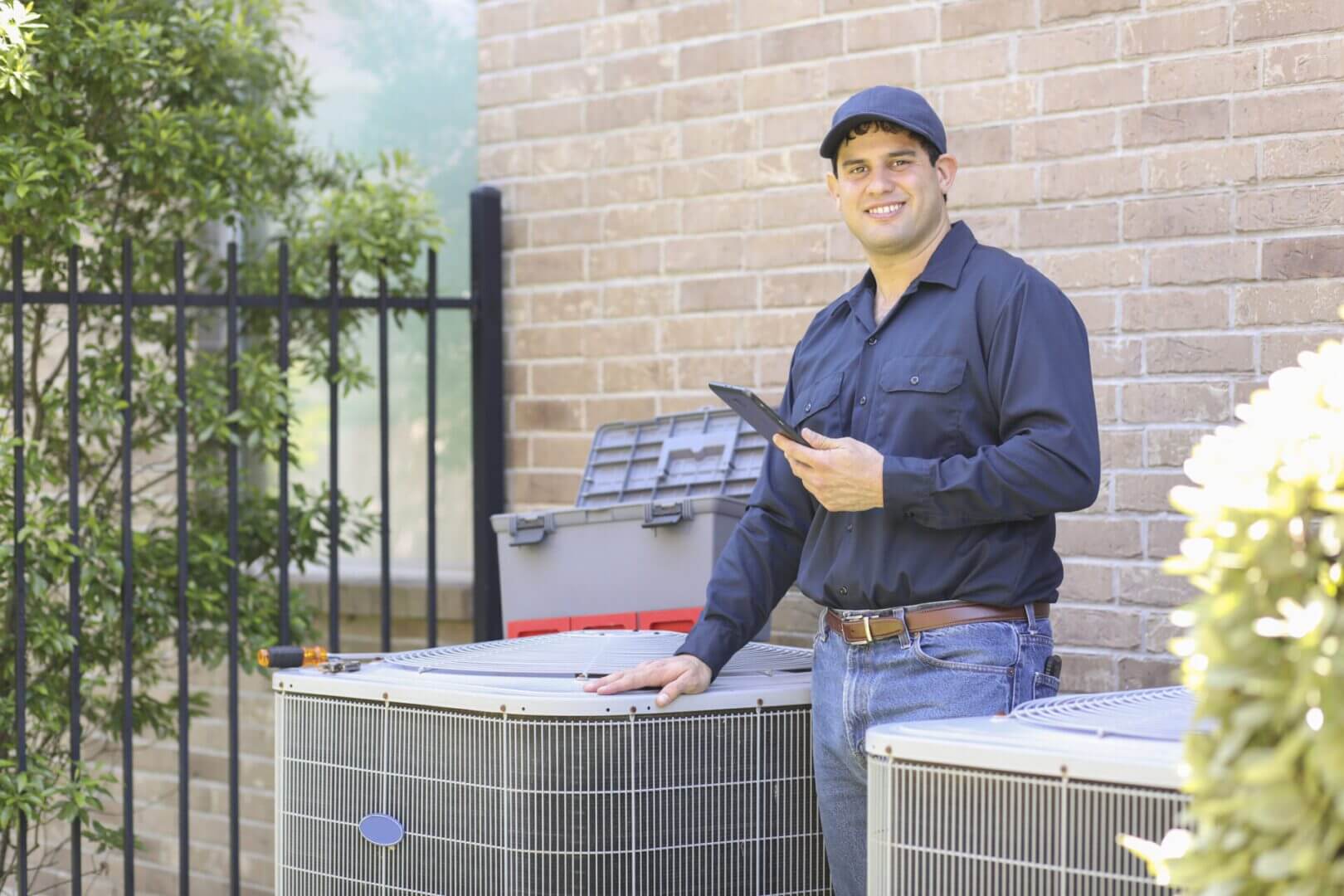 Technician inspecting HVAC units outdoors with a clipboard.